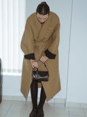 Reco Casa rosewood leather baguette bag with key charm, worn crossbody by a model in a tan coat.