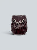 Reco Clam Shell crossbody bag in deep red coral patent leather with kiss-lock clasp and natural pleats.