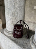 Reco Clam Shell crossbody bag in deep red coral patent leather with kiss-lock clasp and natural pleats.