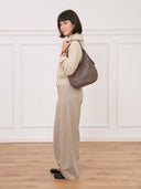 Reco Halston crescent shoulder bag in raw umber Togo calfskin worn by a woman in a neutral outfit