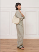 Model wearing a Reco. Halston white Togo calfskin shoulder bag with a minimalist curved silhouette.