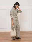Reco Halston white Togo calfskin hobo bag held by a woman in a sage green linen set against a neutral wall.
