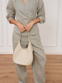Reco Halston white Togo calfskin hobo bag with a minimalist silhouette held by a woman in a sage green linen set.