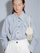 Reco ivory leather compact baguette bag with adjustable strap and signature key charm, worn crossbody by a model.