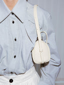 Reco. ivory leather compact baguette bag with adjustable strap and key charm, worn crossbody.