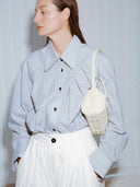 Reco ivory leather compact baguette bag with adjustable strap and signature key charm, worn crossbody by a model.