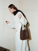 Reco Key Hobo (22) rosewood pebbled leather hobo bag with key closure and white stitching, worn by a woman in a cream jumpsuit and black scarf.