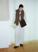 Reco Key Hobo (22) rosewood leather hobo bag with key closure and white stitching, worn by a model in a vest and white pants.