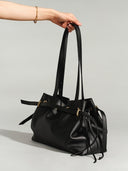 Reco L'erreur black leather drawstring bucket bag with gold hardware and adjustable straps.