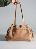 Reco L'erreur tote bag in maple sugar nubuck leather with drawstring closure and adjustable straps.