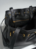 Reco L'erreur black Napa leather dumpling bag with gold hardware, drawstring closure, and interior zip pocket.