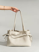 Reco. L'erreur dumpling bag in Fog White pebbled Togo calfskin with drawstring top and shoulder straps.