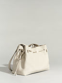 Reco. L'erreur dumpling bag in Fog White pebbled Togo calfskin with a drawstring top and flat geometric base.