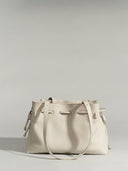 Reco. L'erreur dumpling bag in Fog White pebbled Togo calfskin with a drawstring top and structured flat base.