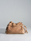 Reco L'erreur dumpling bag in maple sugar suede with a soft peach-skin texture and drawstring closure.
