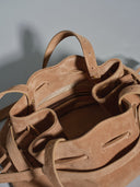 Reco L'erreur dumpling bag in maple sugar suede with a soft peach-skin texture and drawstring closure.