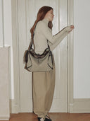Reco Wander (L) bag in acorn canvas with dark brown leather trim and a compass charm, worn by a model.