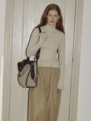Reco Wander bag in beige canvas with dark brown leather trim and a compass charm, worn by a model.
