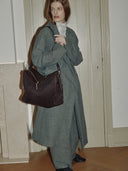Reco Wander bag in espresso brown suede with a flying-tail zipper and compass charm, worn by a model.