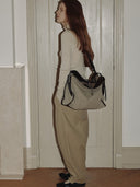 Reco Wander (L) bag in tan canvas with dark brown trim and a compass charm. A relaxed, slouchy shoulder bag.